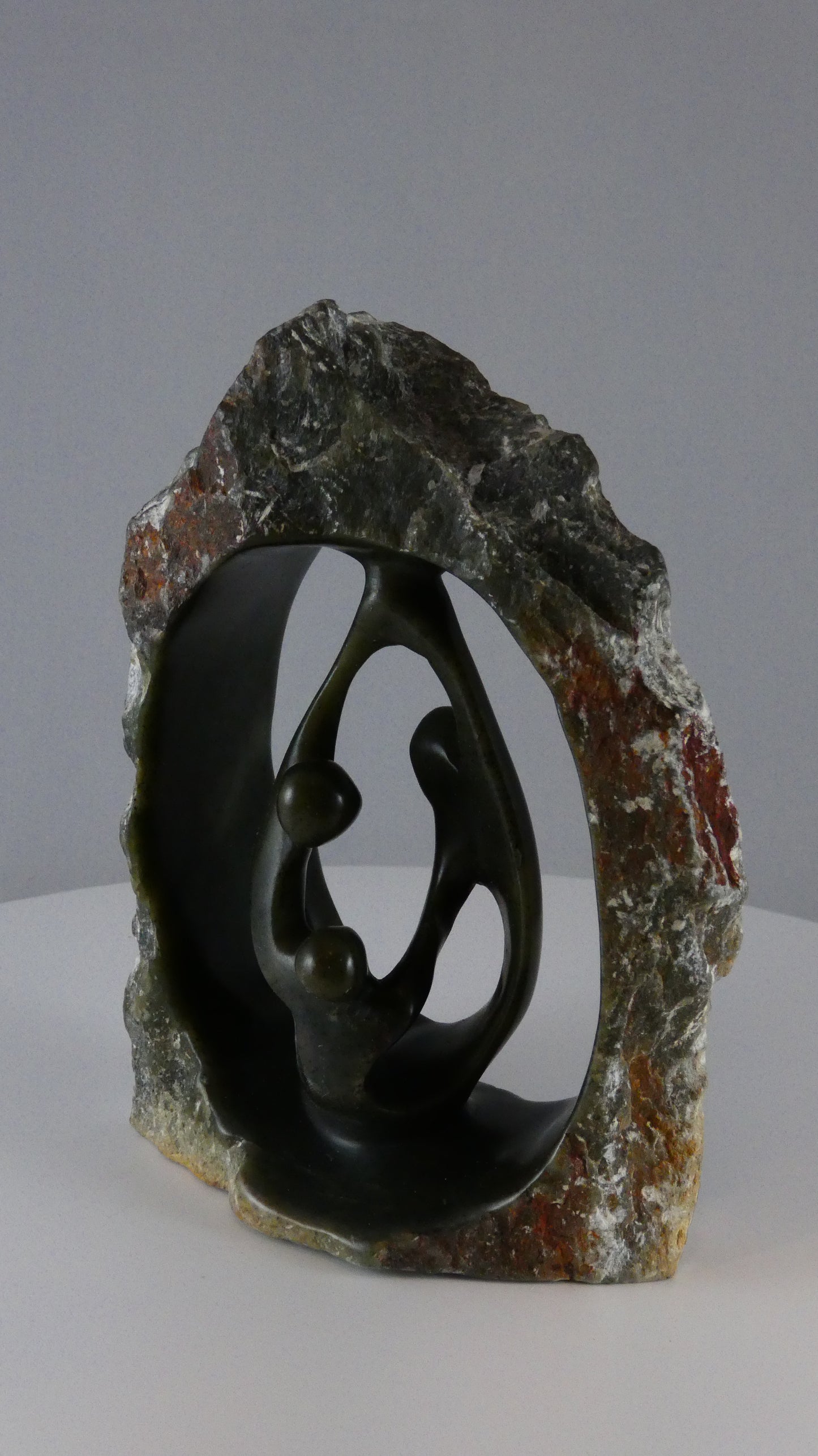 Stenen beeld, 3 personen, 16 cm hoog, buitenzijde ruw, binnenzijde glad afgewerkt