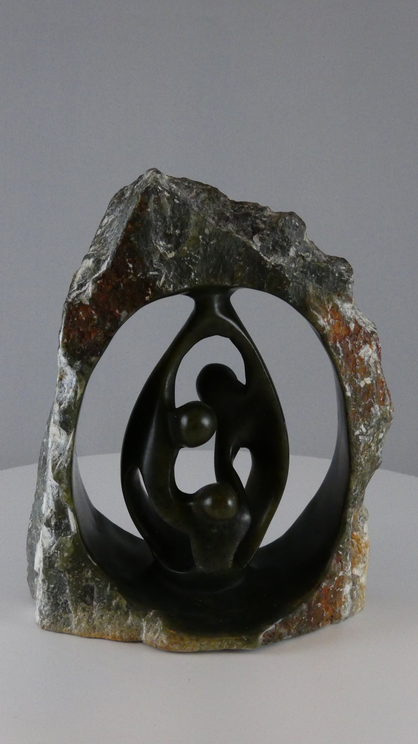 Stenen beeld, 3 personen, 16 cm hoog, buitenzijde ruw, binnenzijde glad afgewerkt