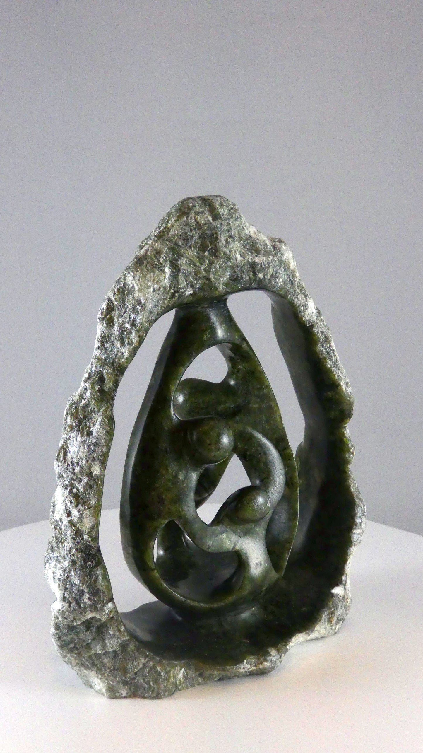 Stenen beeld, 4 personen, 19 cm hoog, buitenzijde ruw, binnenzijde glad afgewerkt